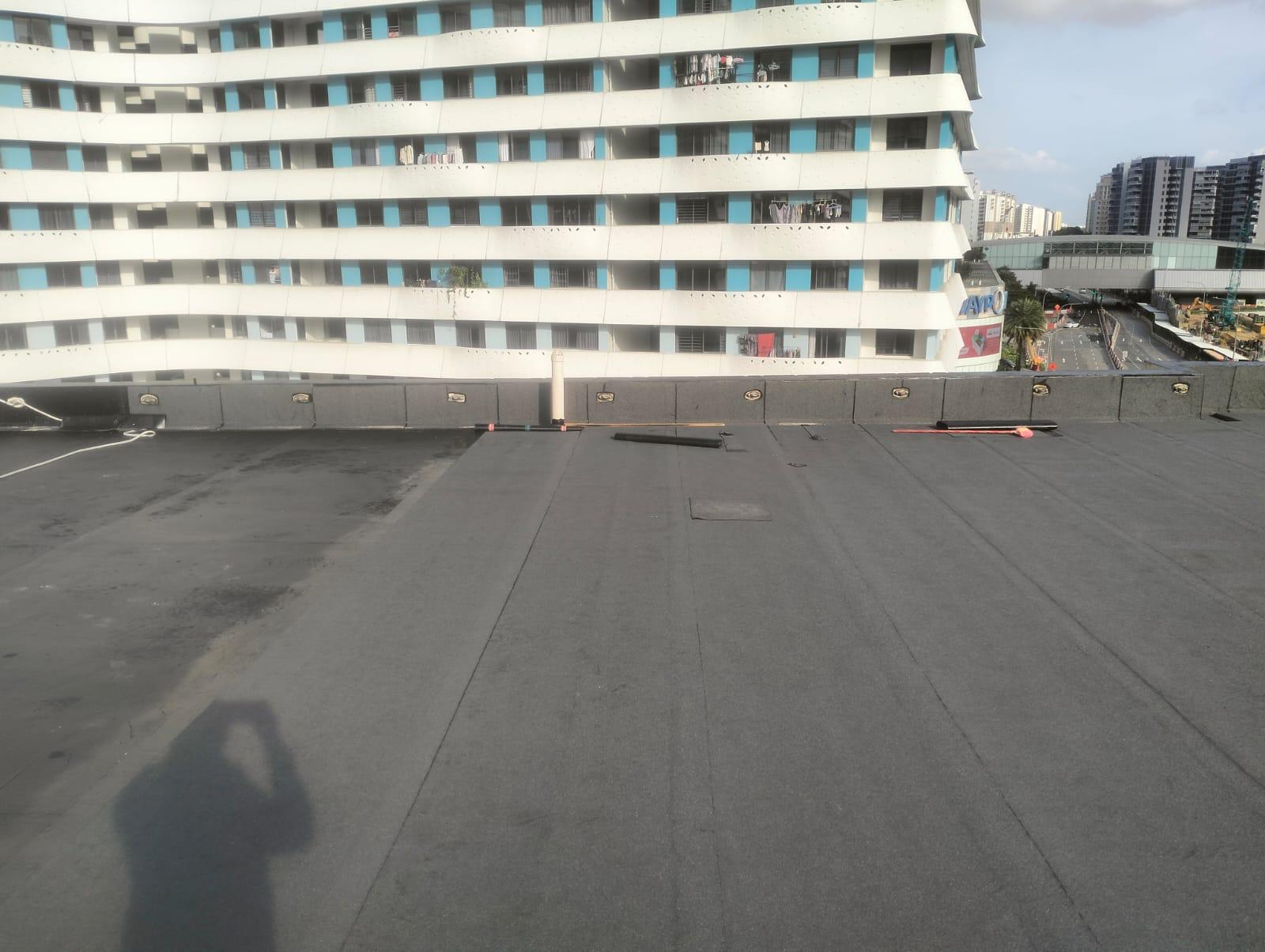 Bituminous SBS torch-on waterproofing membrane laid on a Singapore HDB block rooftop — large flat-field podium scope