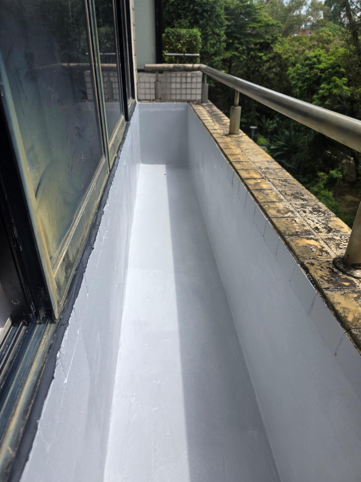 Grey PU waterproofing membrane applied to a balcony planter trough next to sliding-glass door and railing in Singapore